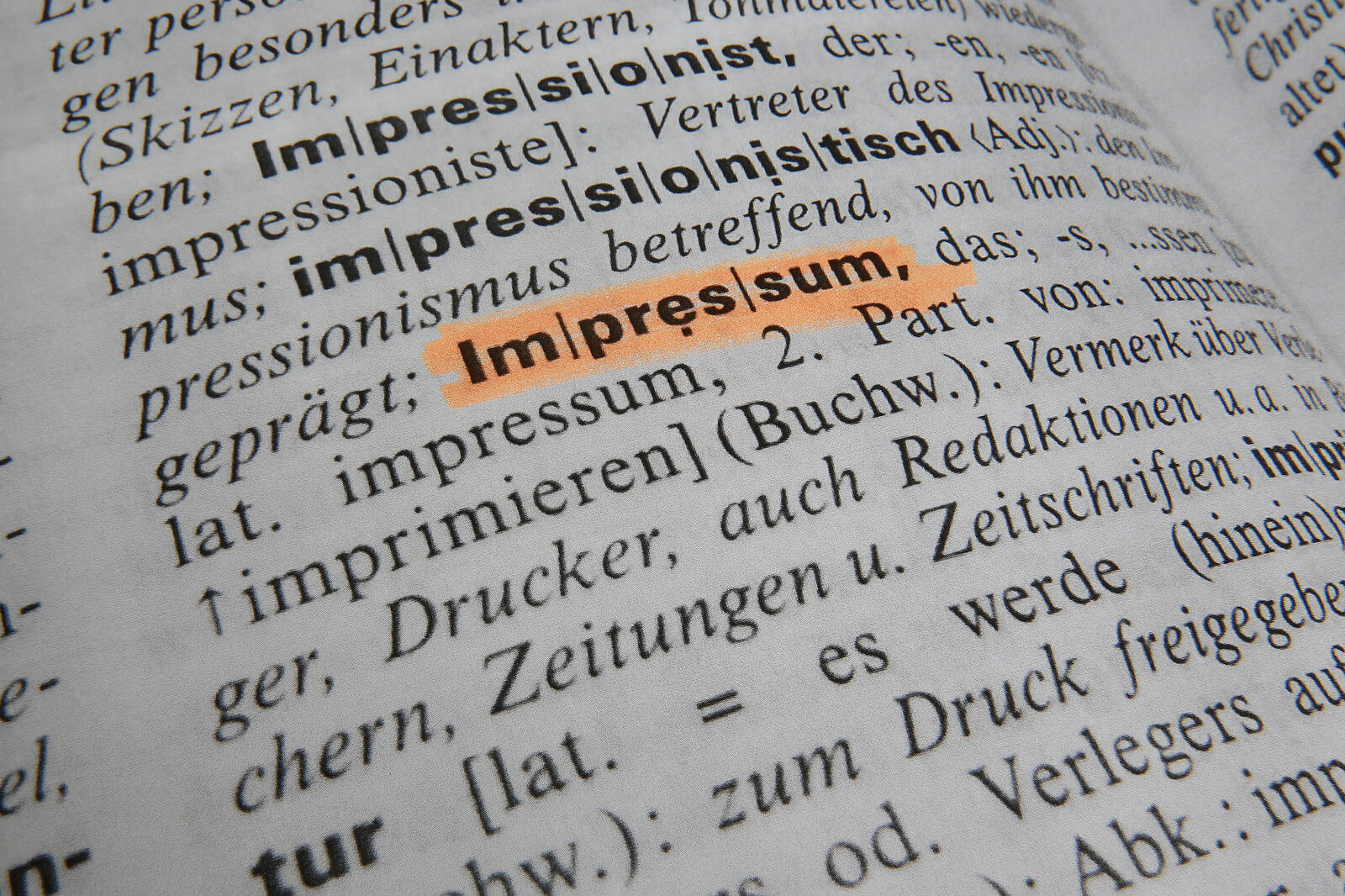 Aufgeschlagene Lexikonseite, Impressum ist mit orangenem Textmarker angestrichen